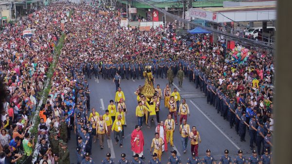 Barefoot Hijos del Nazareno carry the statue of the Black Nazarene on their shoulders during the Traslación’s procession as it approaches the Jesus Nazareno Parish-Shrine of the Black Nazarene at Claro M. Recto Avenue, January 9. Philippine National Police (PNP) personnel served as a human barricade to prevent attendees from barging into the statue and possibly causing damage. (Photo: DCC/PIA-10)