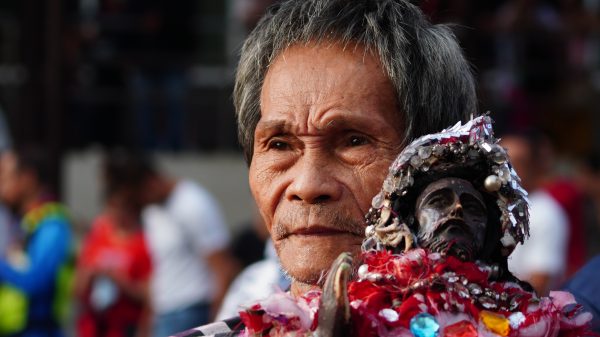 A devotee is seen clutching a cross-less replica of the Black Nazarene outside the doors of the Jesus Nazareno Parish-Shrine of the Black Nazarene. (Photo: SAYU/PIA-10)