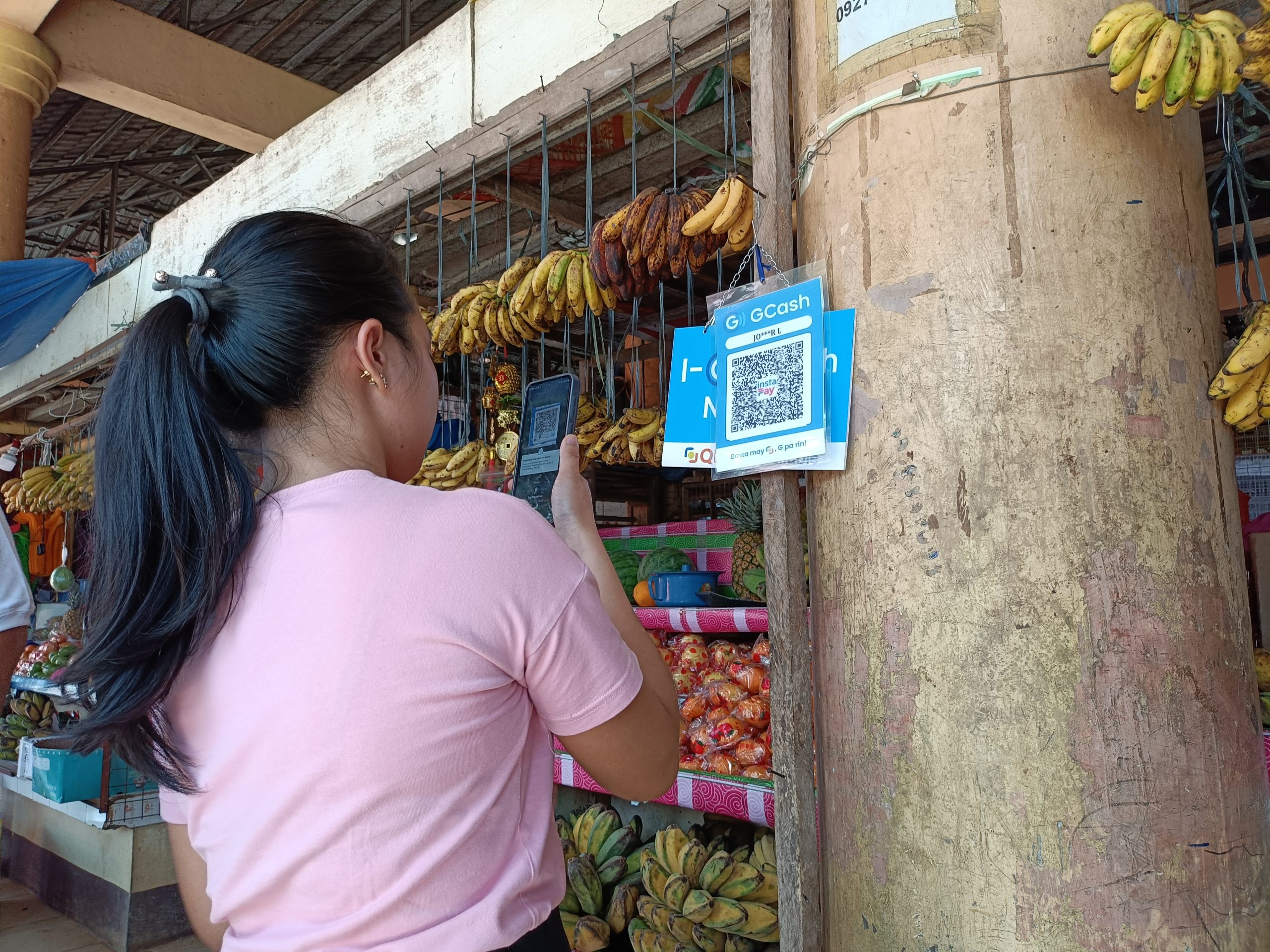 A customer at one of the fruit stands at the Tankulan Public Market in Manolo Fortich, Bukidnon, pays for her purchased mango fruit using a digital payment app. The local government unit of Manolo Fortich, Bukidnon, in partnership with the Bangko Sentral ng Pilipinas, Cagayan de Oro Branch, and the Department of the Interior and Local Government, launched the Paleng-QRPh Plus, January 31. (Photo: SAYU/PIA-10)